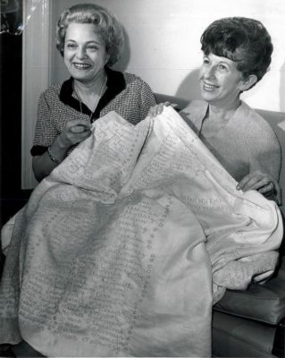 In 1965 after 11 years of work, Mrs. Morris Wheeler and Mrs. Bud Saunders showed off the completed Jewish Home and Hospital for the Aged tablecloth with more than 1200 names of individuals who made donations. (image courtesy Rauh Jewish History Program & Archives)